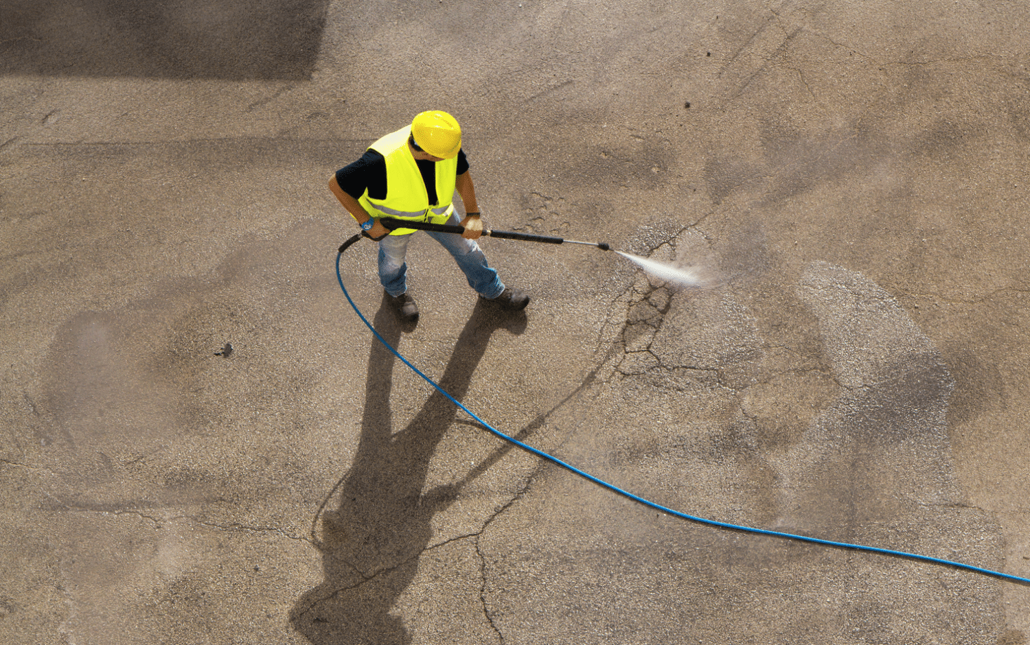 A man in a yellow vest is using a hose