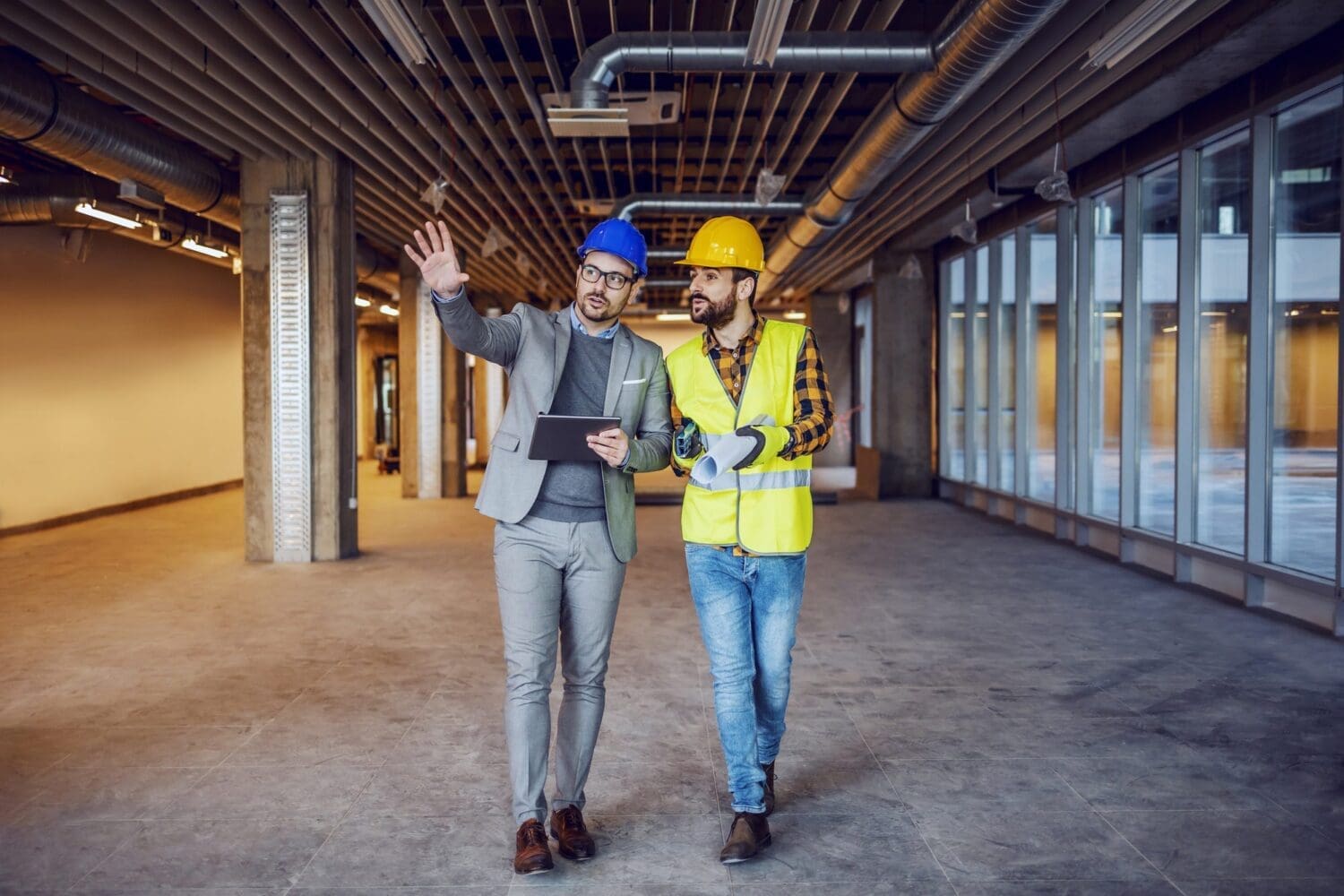 Dedicated innovative architect holding tablet and explaining his ideas to construction worker.