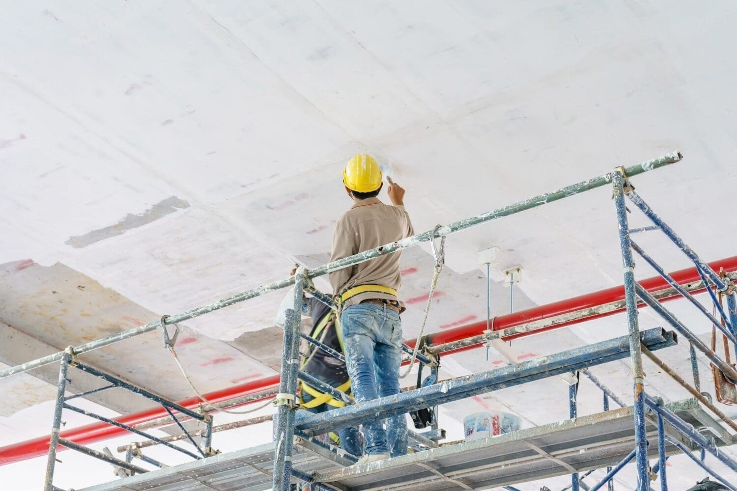 Construction workers on scaffolding tower painting and renovating building floor in construction site.